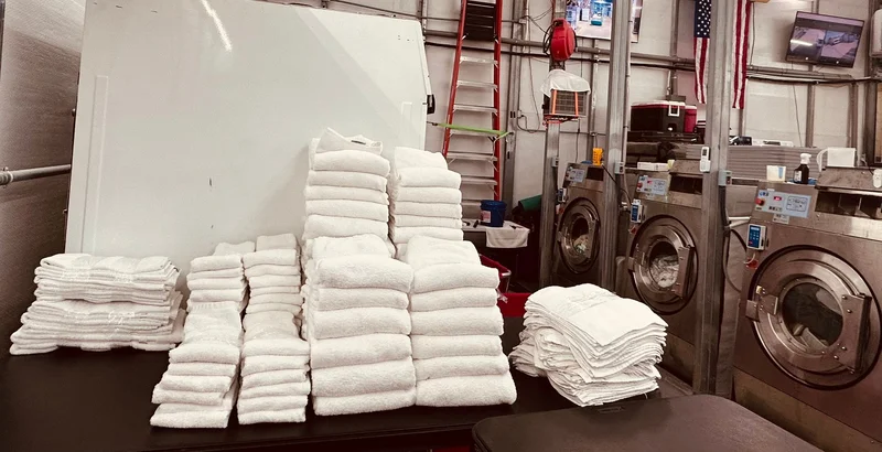 Stacks of white folded towels inside Dee's commercial laundry facility, Panama City Beach
