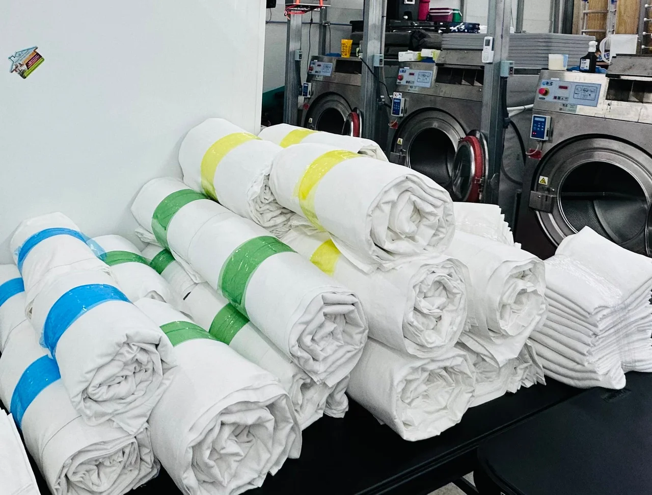 Colour-coded rolled bed sheets sorted by property — Dee's Linen Service Panama City Beach
